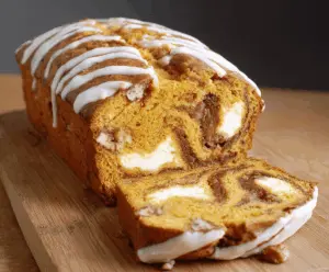 Swirled pumpkin cream cheese bread sliced on a plate, showcasing its moist texture and creamy swirl, perfect for fall desserts or breakfast