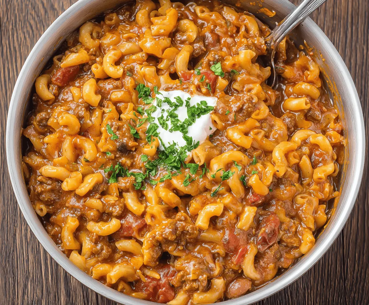 A delicious bowl of chili mac featuring seasoned ground beef, creamy cheese sauce, and tender macaroni pasta topped with chopped green onions.