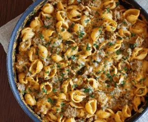 Creamy beef and pasta shells in a skillet, topped with fresh herbs, served in a bowl for a hearty one-pot meal