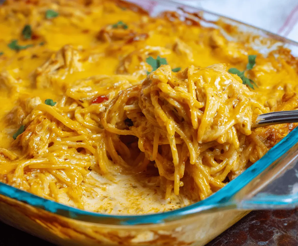 Creamy and spicy Southern Chicken Spaghetti Casserole topped with melted cheese and fresh herbs, served in a baking dish.