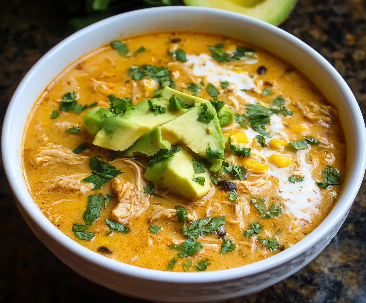 Creamy chicken enchilada soup in a bowl with melted cheese and fresh cilantro garnishes.