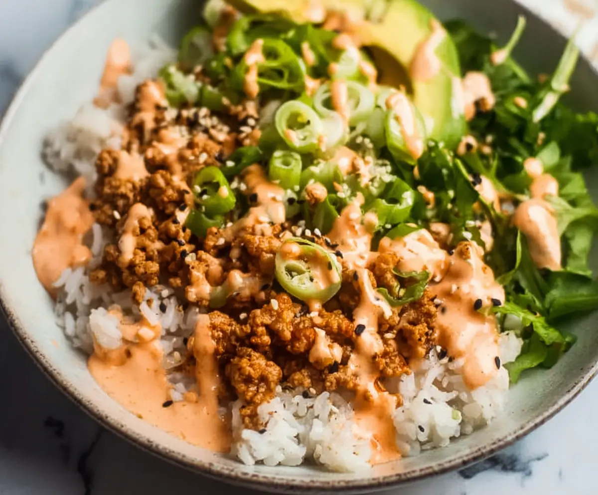 Delicious ground turkey rice bowls topped with a creamy Bang Bang sauce and fresh herbs.