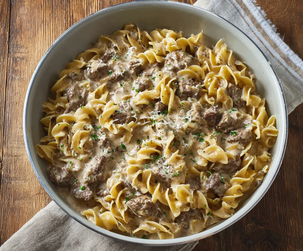 Creamy beef stroganoff served over egg noodles with fresh herbs and a rich brown gravy.