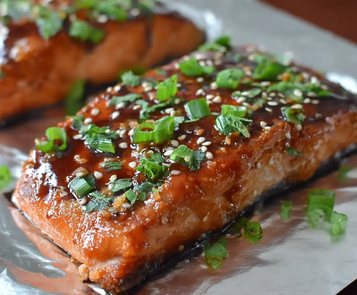 Delicious glazed teriyaki salmon fillet served with fresh vegetables on a plate.
