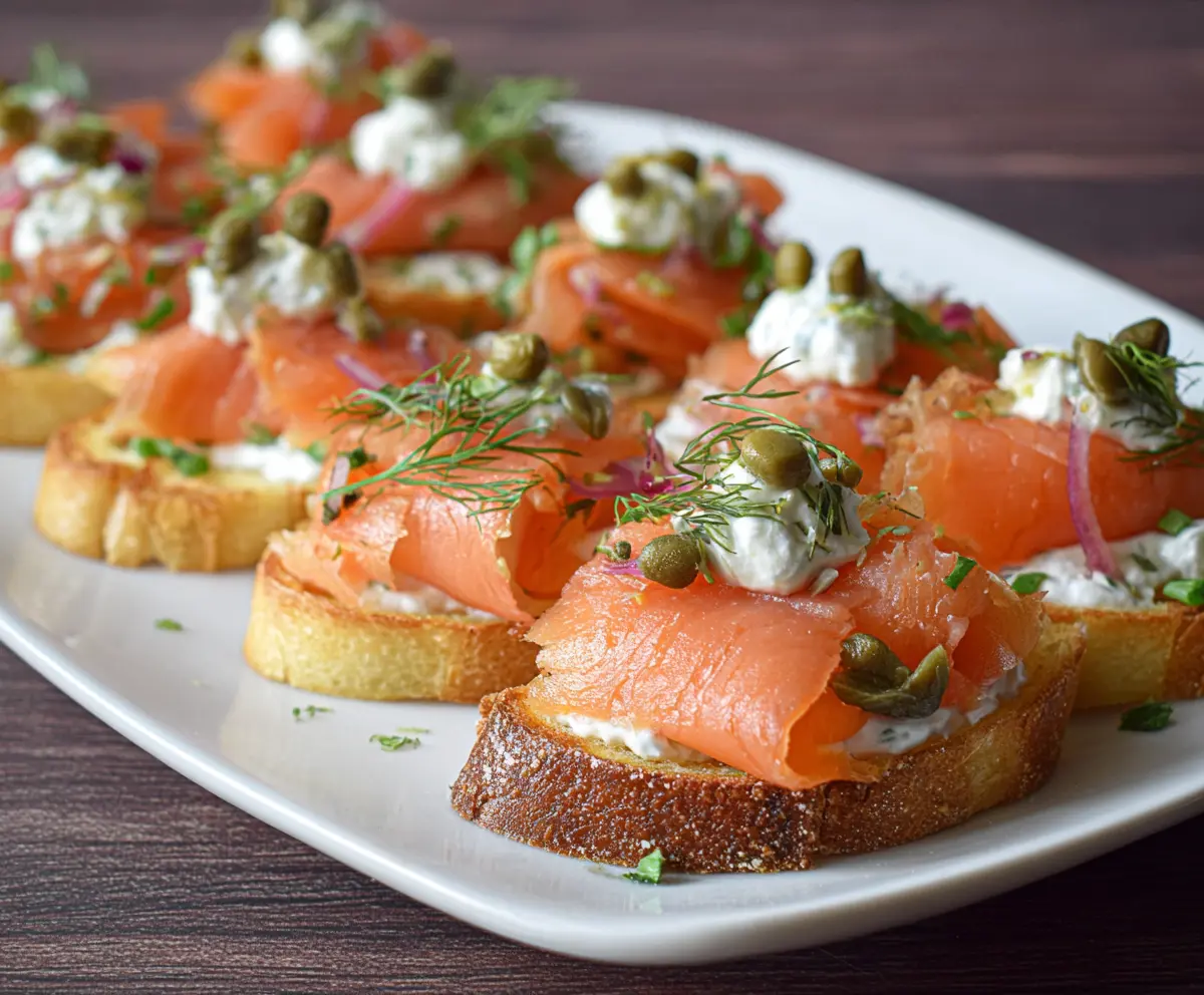 Delicious smoked salmon bruschetta topped with fresh herbs on toasted baguette slices.