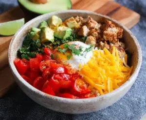 Healthy low carb breakfast burrito bowl with scrambled eggs, vegetables, and cheese in a bowl.